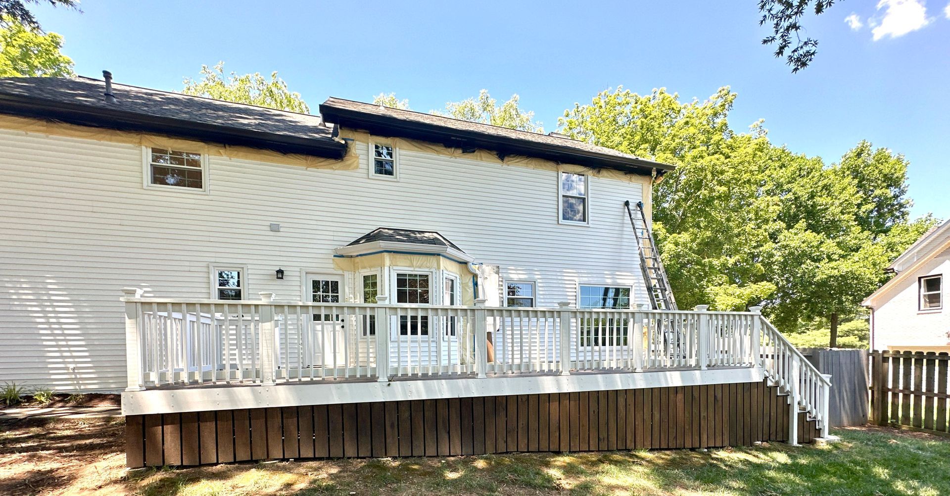 A white house with a large deck in front of it.