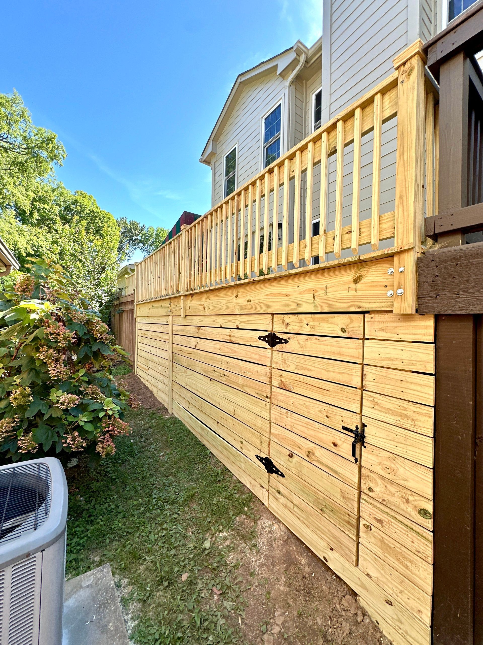 A wooden fence surrounds a house with a deck.