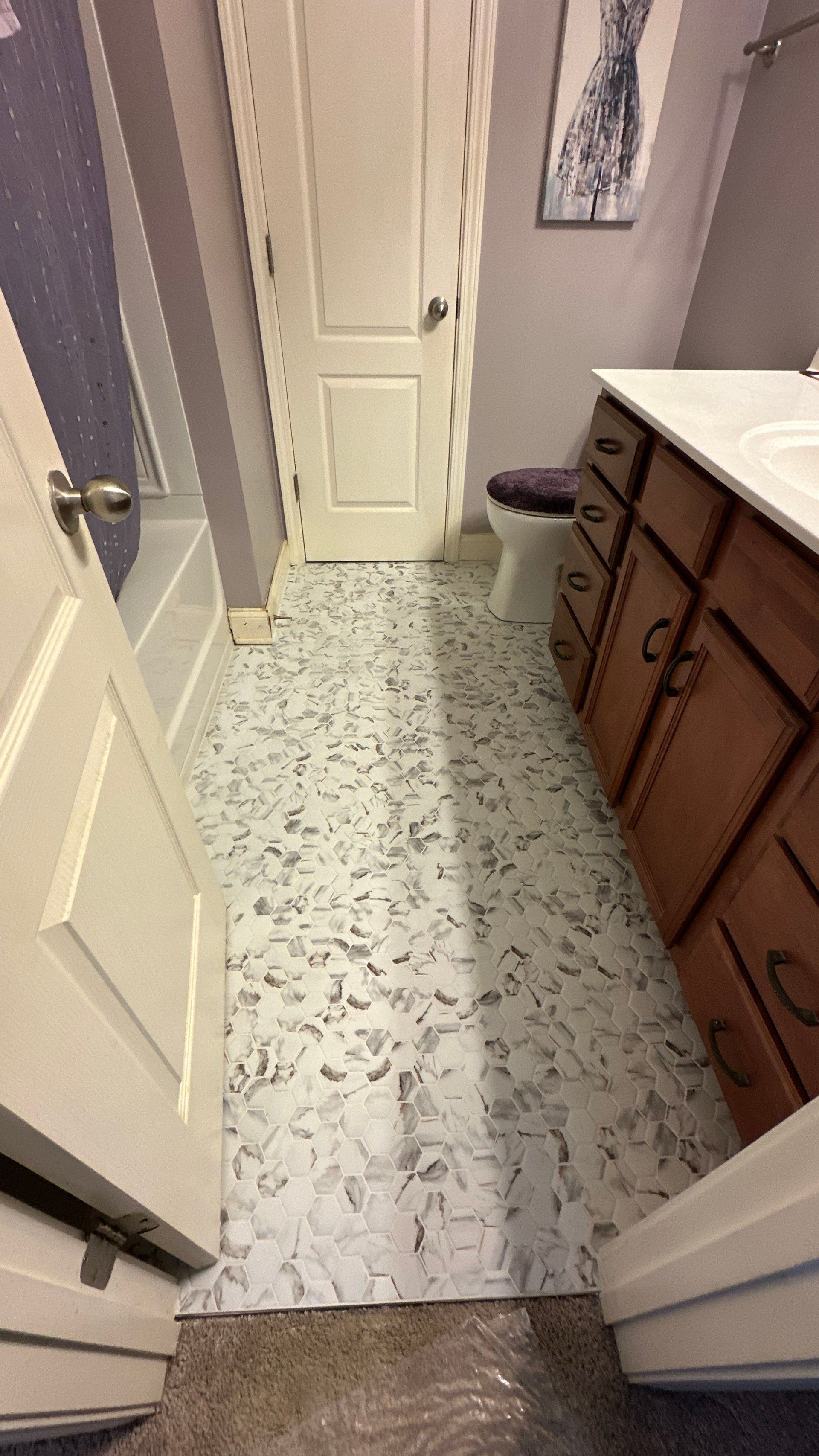 A bathroom with a marble floor , wooden cabinets , a sink and a toilet.