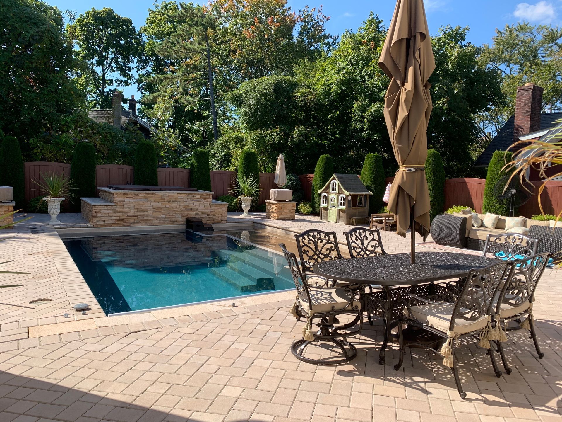 A table and chairs are sitting on a patio next to a swimming pool.