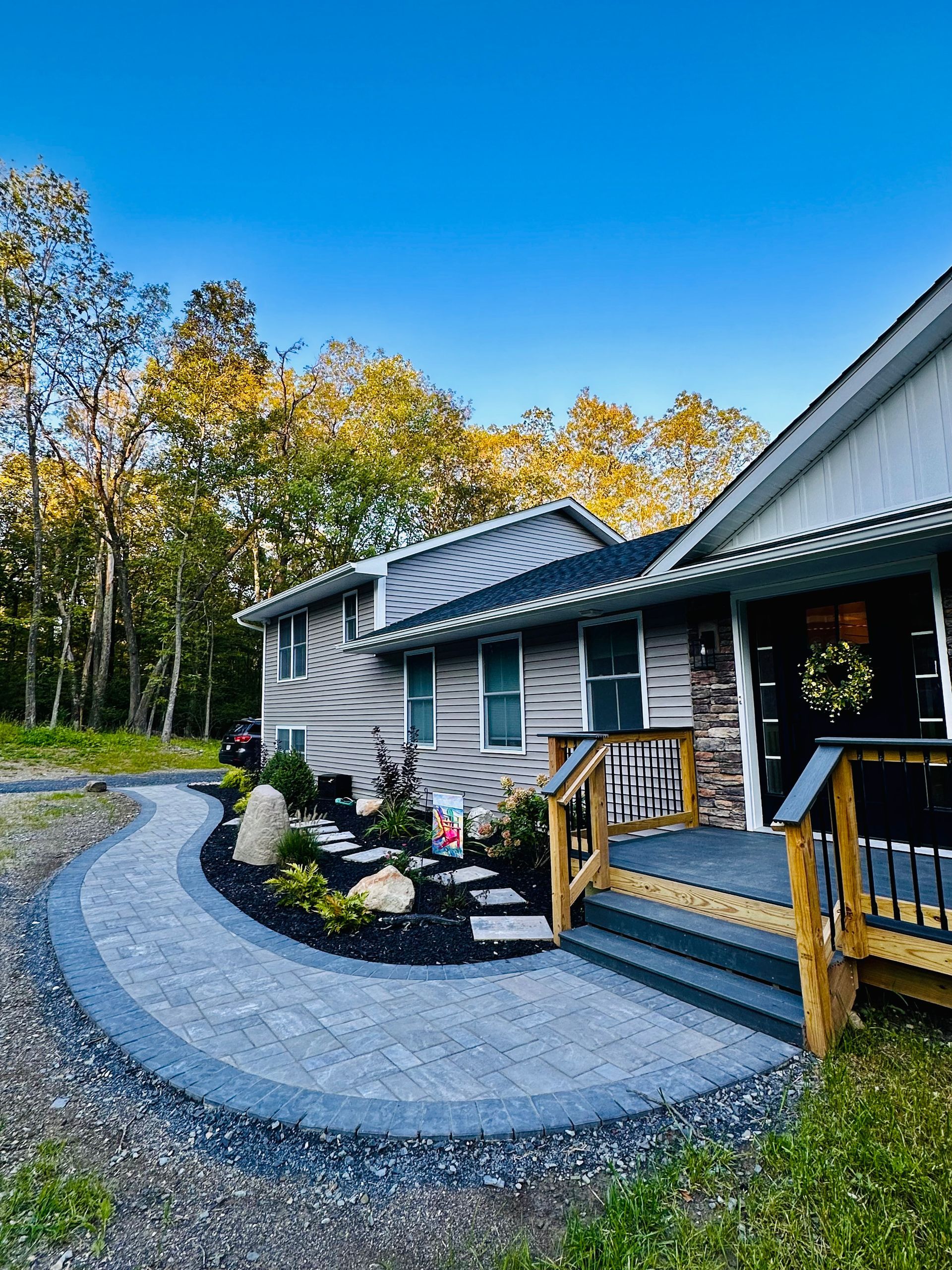 A house with a walkway leading to the front door and a deck.