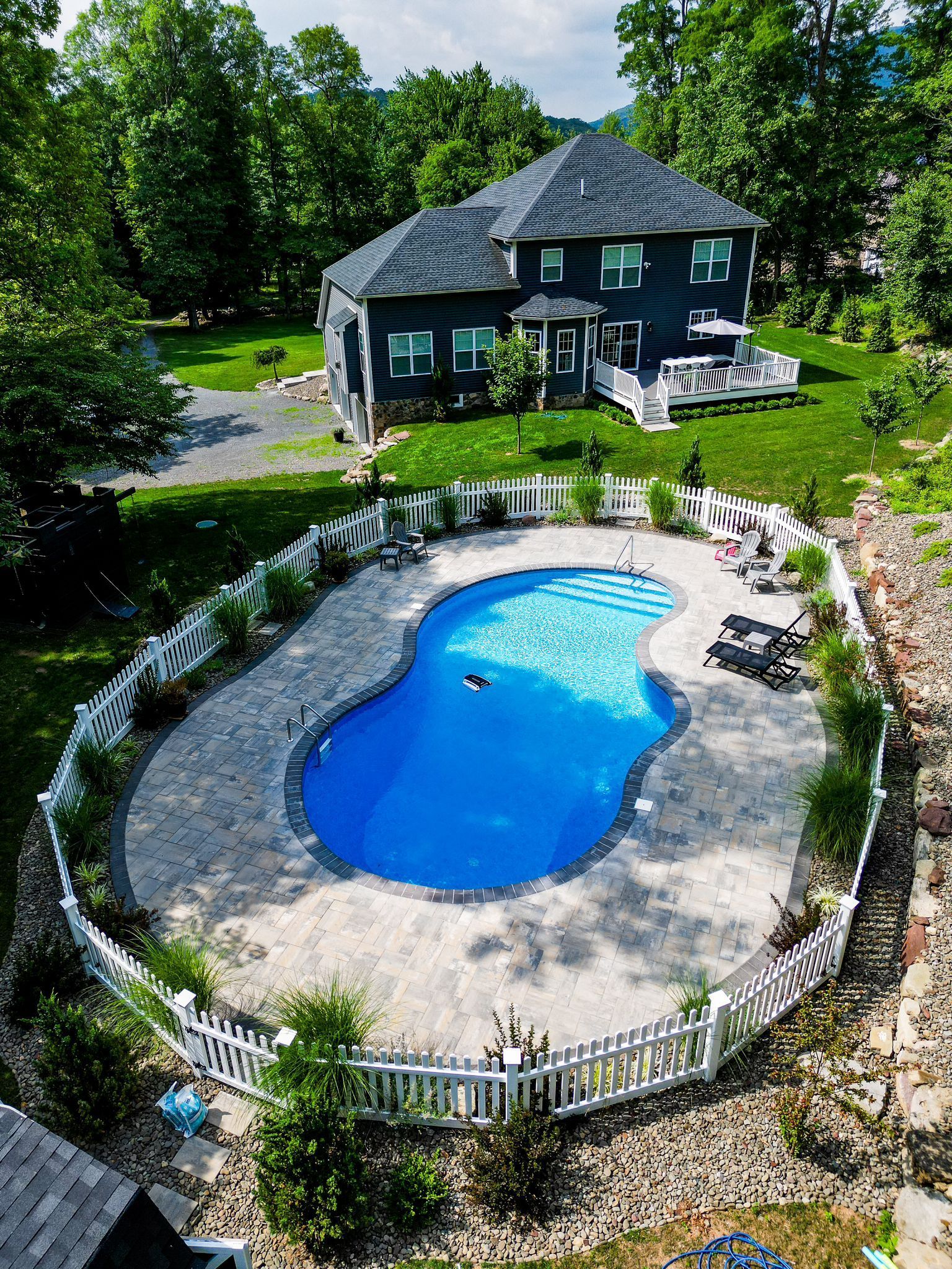 An aerial view of a large swimming pool in front of a house.