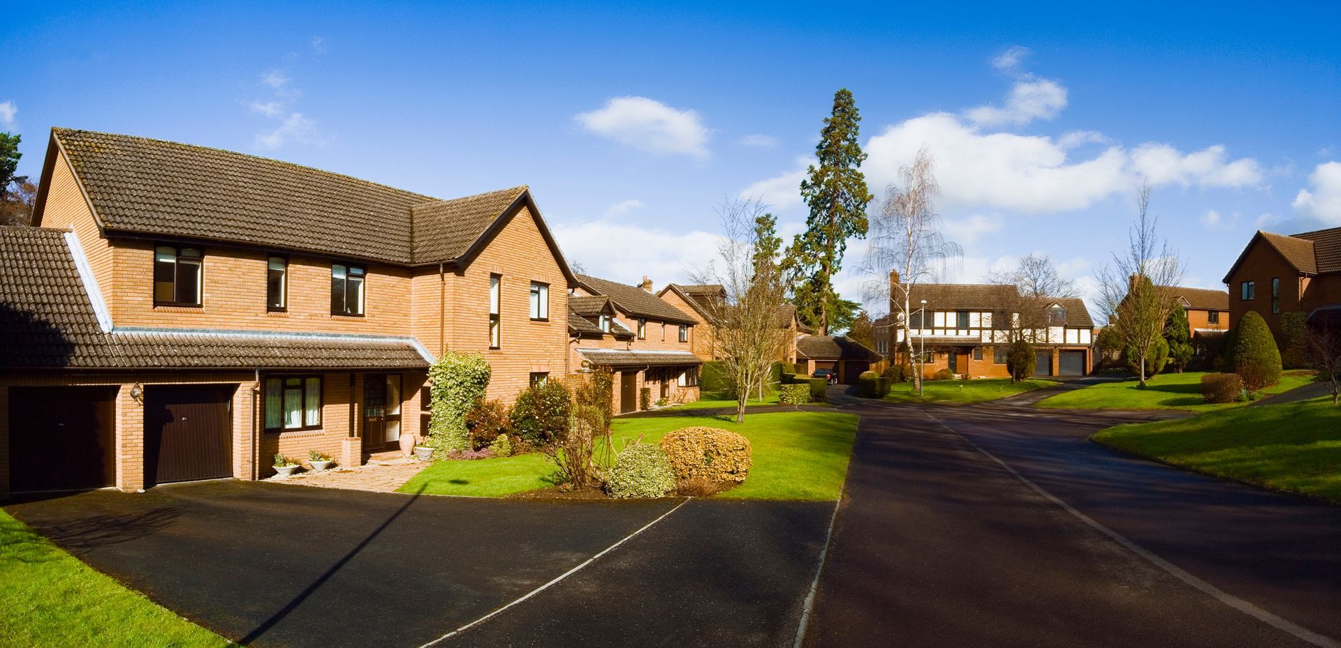 A row of houses in a residential area with a black driveway