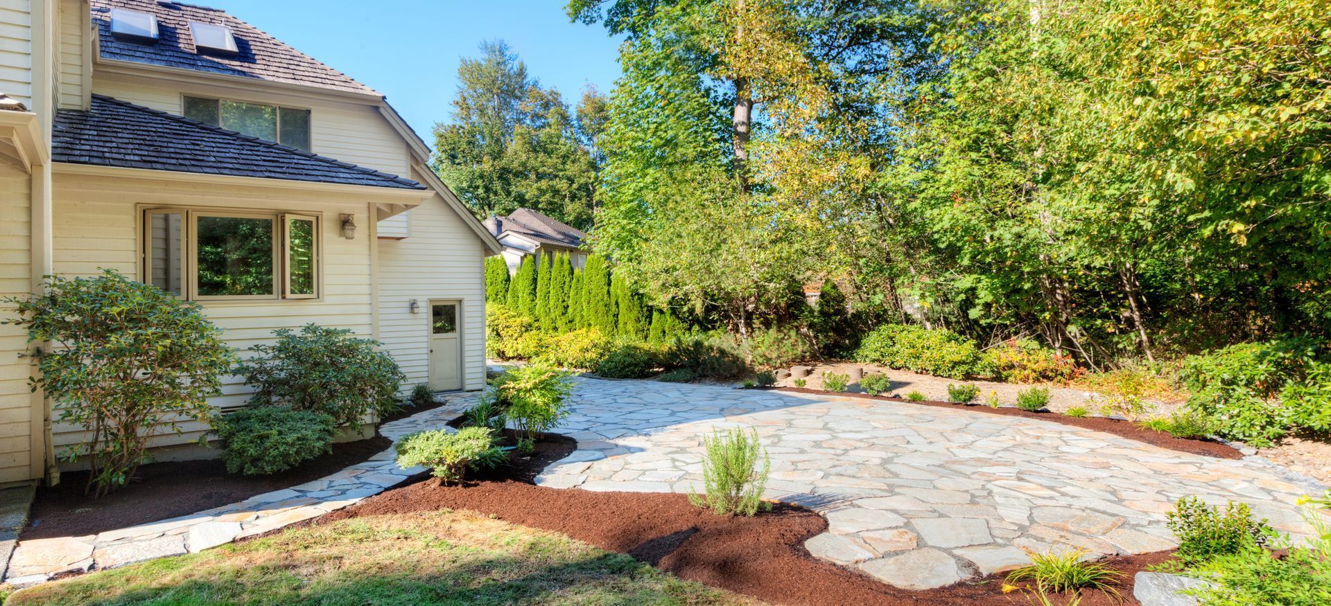 A large white house with a stone walkway leading to it surrounded by trees.