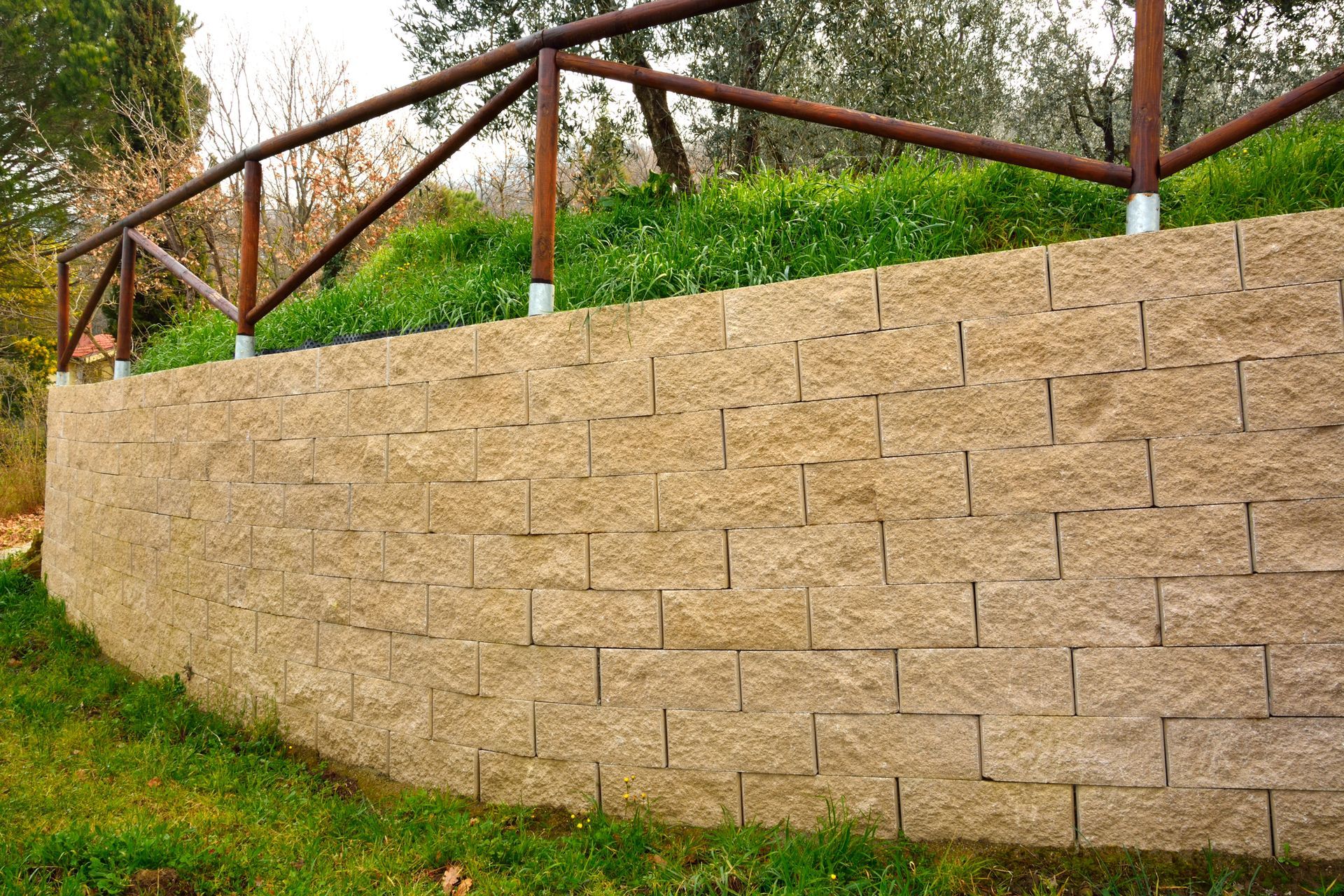 A large stone wall with a wooden fence surrounding it.