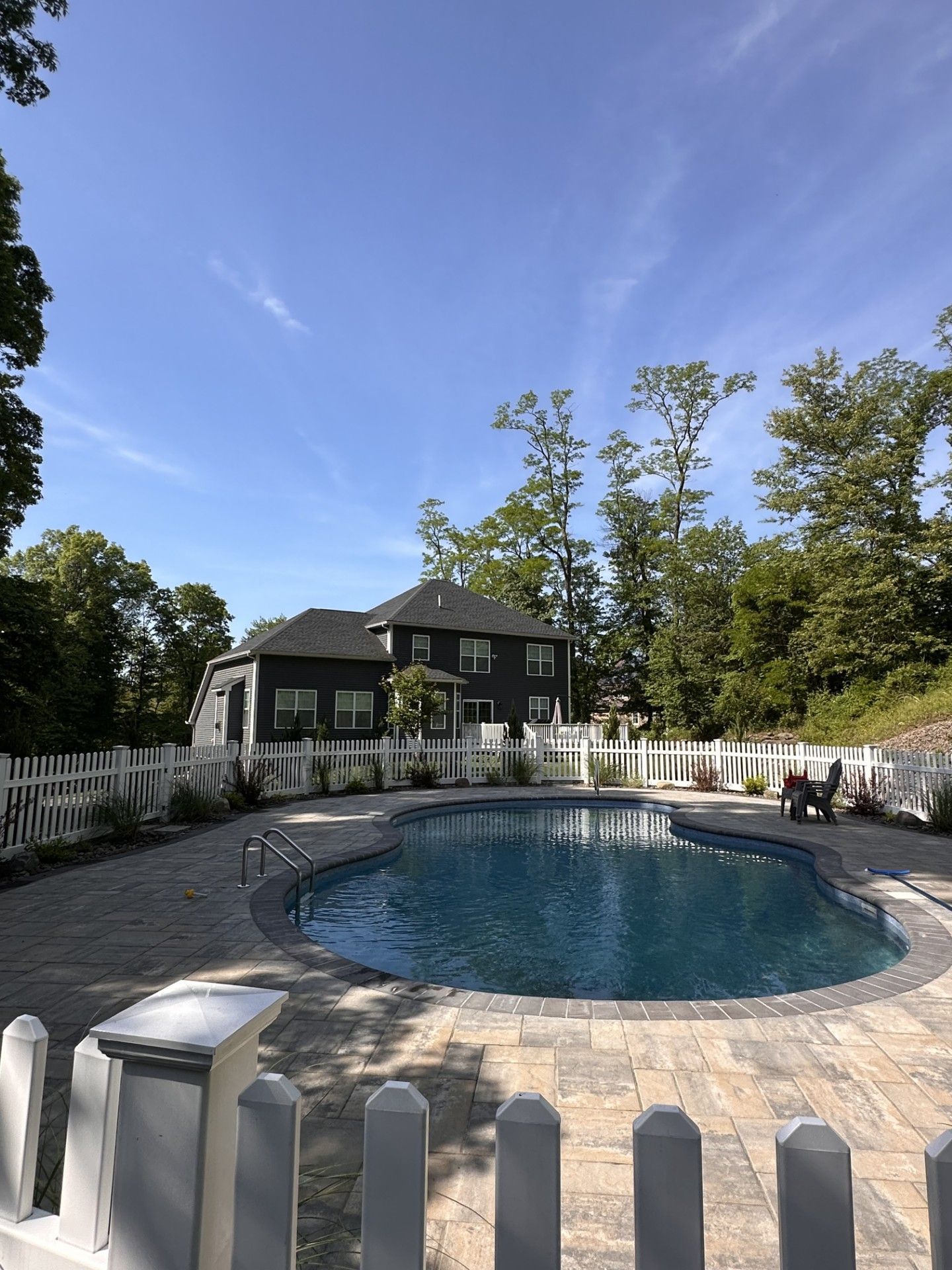 A man is kneeling down in a garden cutting a bush.