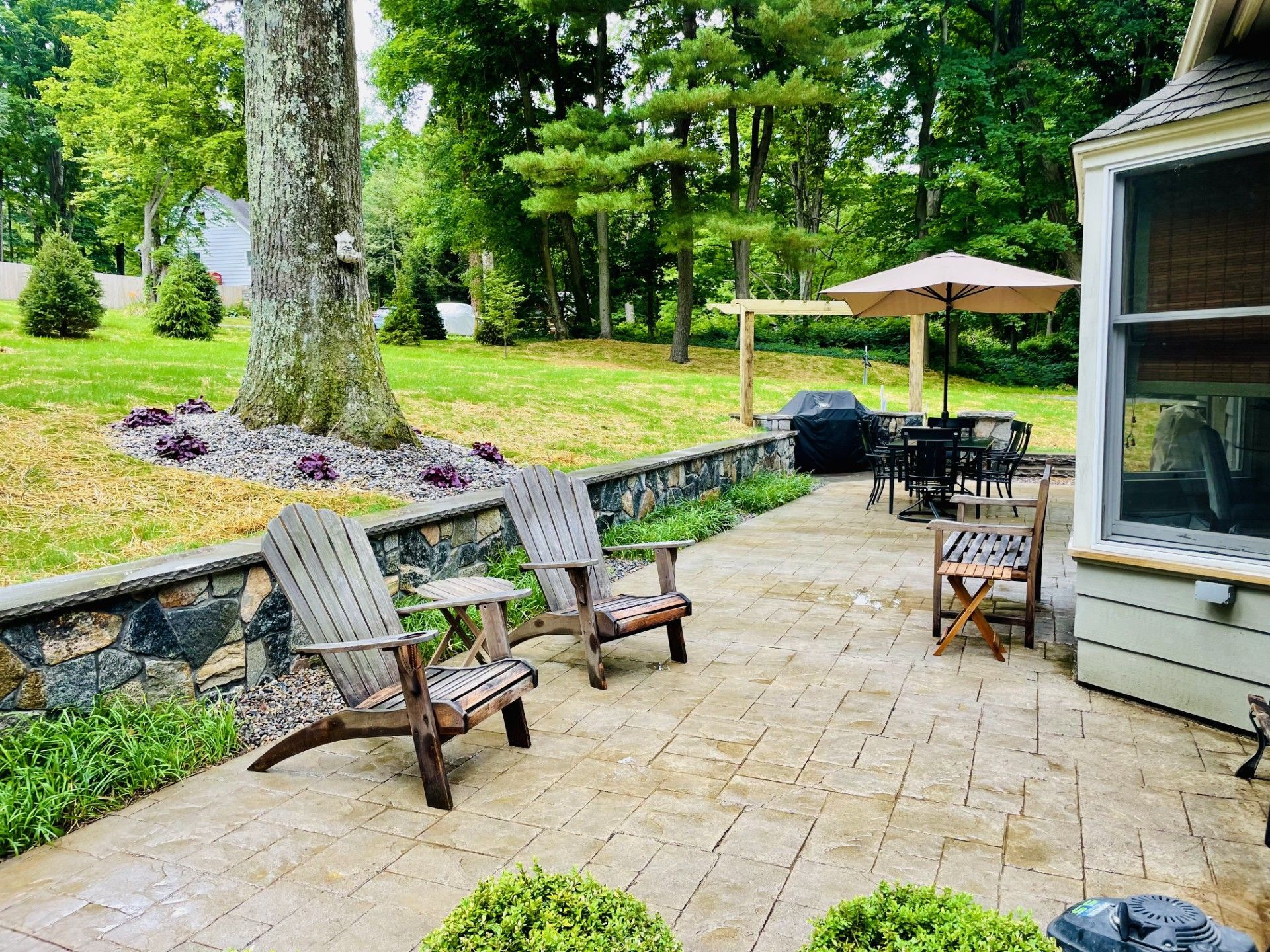 A patio with chairs , umbrellas and a grill.