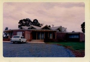 Mid-century modern brick house with a car parked in front on a cloudy day.