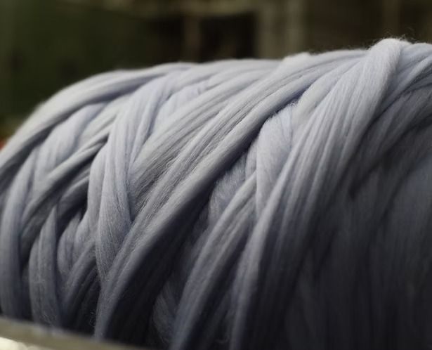 Primo piano di una grande bobina di filato azzurro.