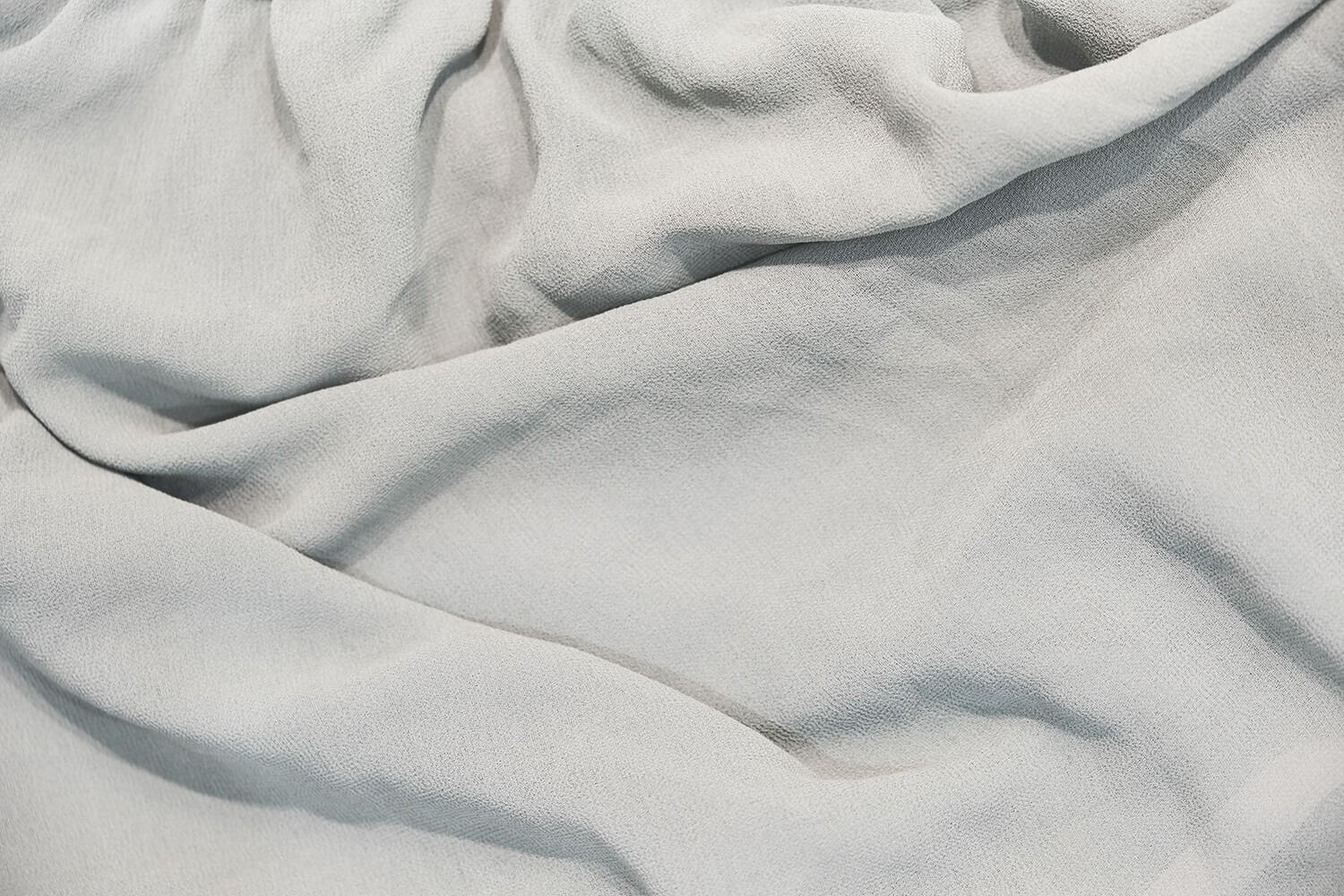 Tessuto in pile grigio testurizzato con morbide pieghe, illuminato dall'alto a sinistra.