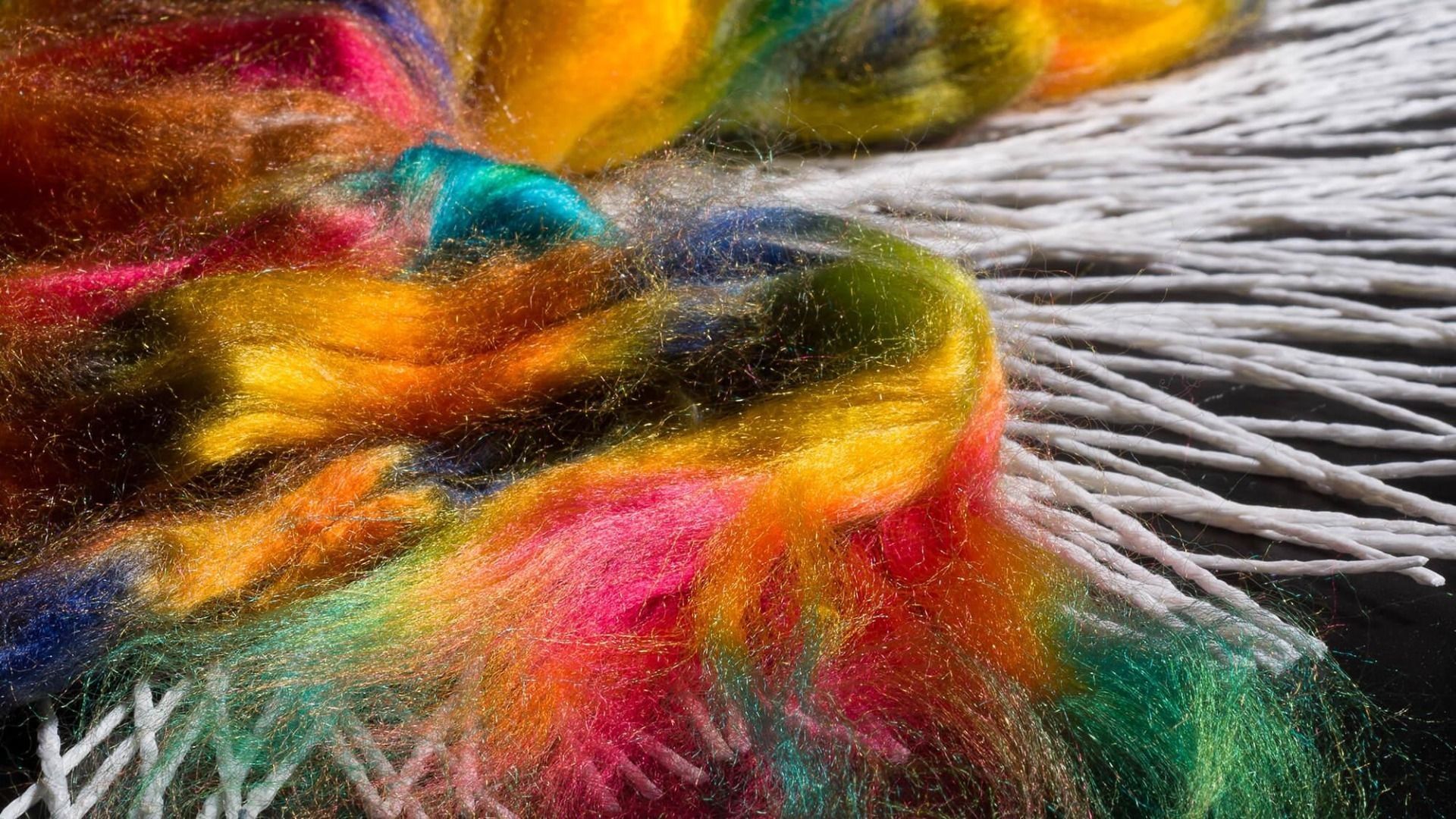 Fili di fibre colorate tinte su supporto bianco.