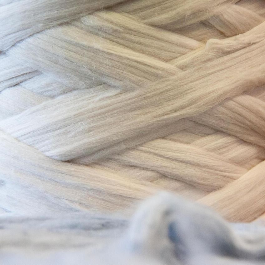 Primo piano di un filato spesso, grigio chiaro, avvolto in un motivo circolare.