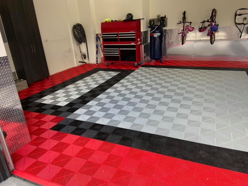 Sol de garage avec dalles emboîtables rouges, noires et grises, outils et supports à vélos.