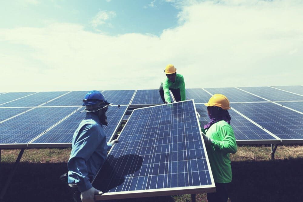 A Group Of People Are Installing Solar Panels On A Roof — Solarblu Pty Ltd In Dapto, NSW