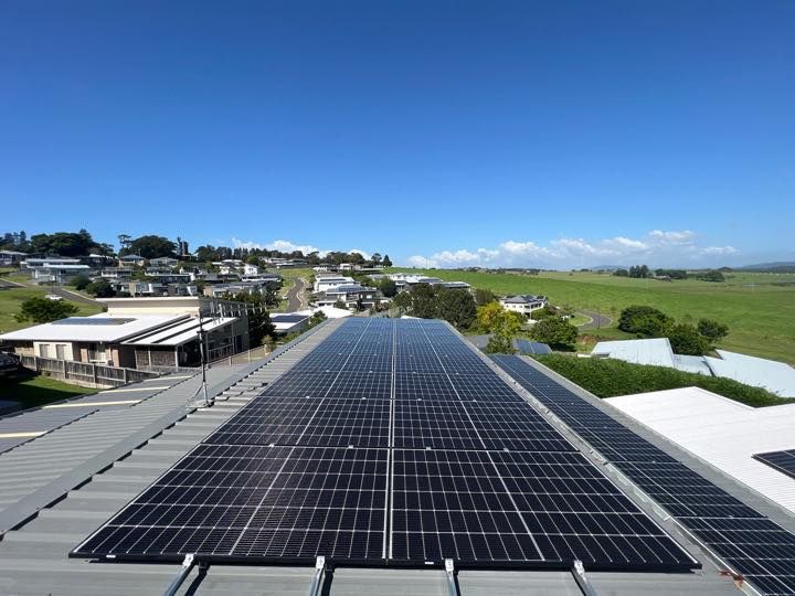 Two Men Are Working On A Solar Panel On Top Of A Building — Solarblu Pty Ltd In Woonona, NSW