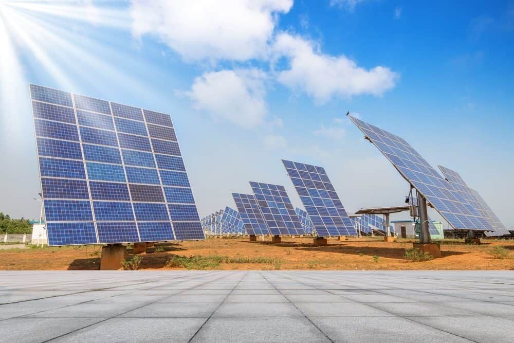 A Row Of Solar Panels In A Field With The Sun Shining Through Them — Solarblu Pty Ltd In Kiama, NSW
