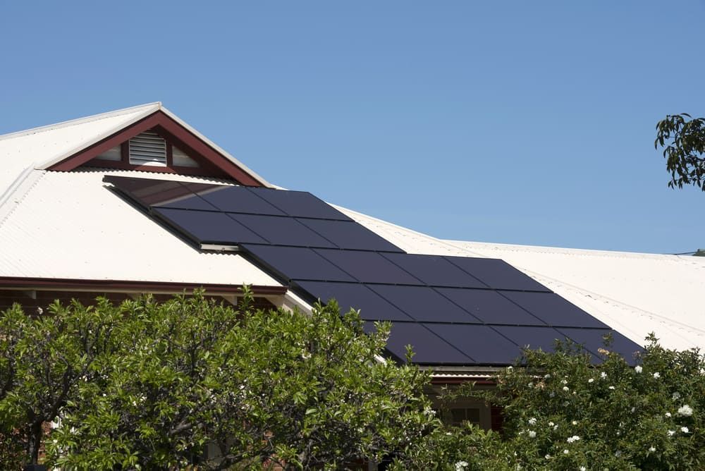 A White House With Solar Panels On The Roof — Solarblu Pty Ltd In Dapto, NSW