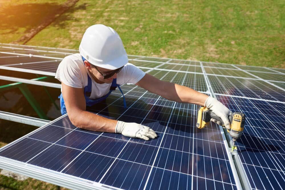 A Man Is Working On A Solar Panel With A Drill — Solarblu Pty Ltd In Berry, NSW