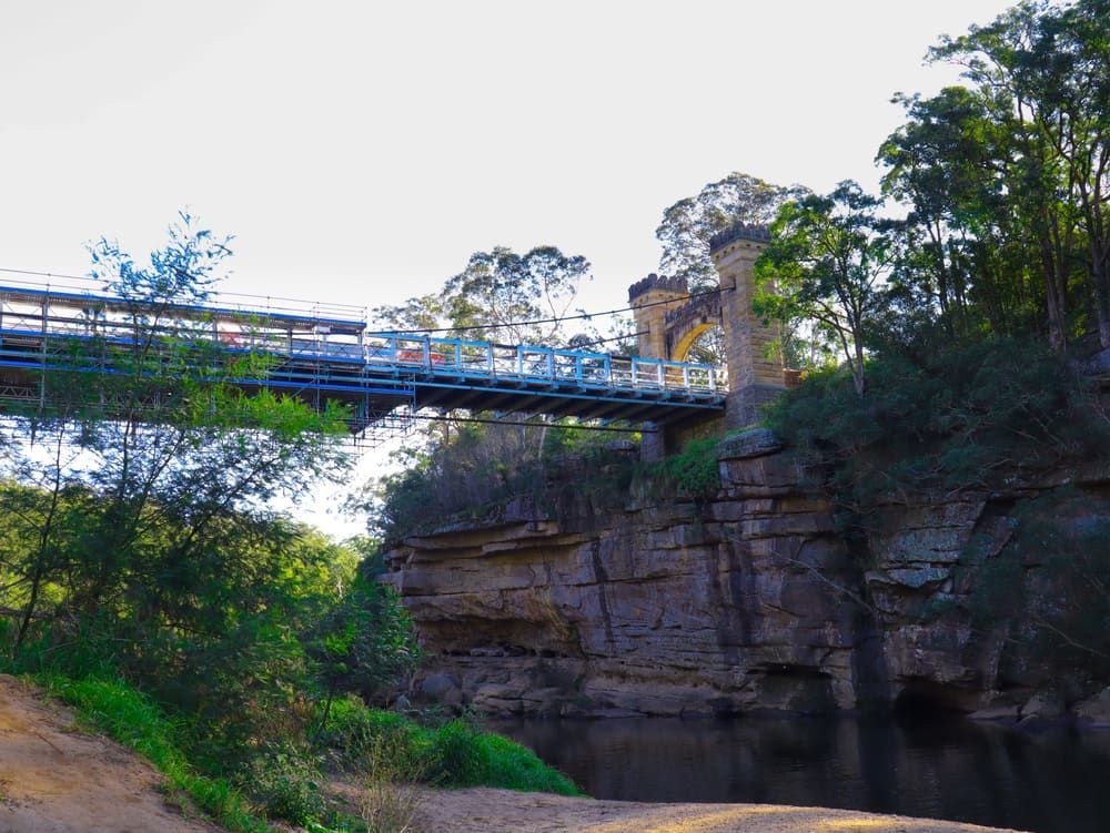 A Bridge Over A River Surrounded By Trees And Rocks — Solarblu Pty Ltd In Berry, NSW