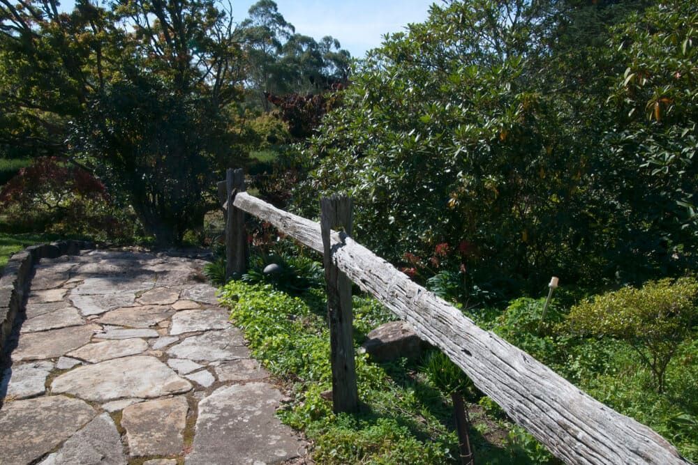 A Wooden Fence Surrounds A Stone Walkway In A Park — Solarblu Pty Ltd In Bowral, NSW