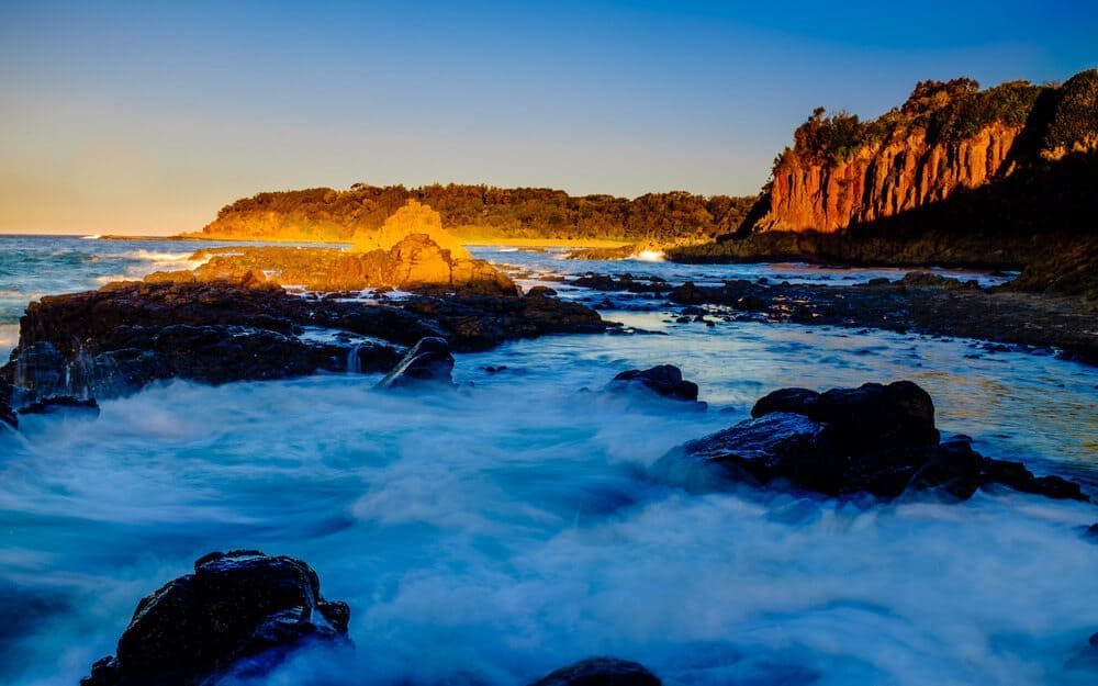 A Rocky Shoreline With Waves Crashing Against The Rocks At Sunset — Solarblu Pty Ltd In Kiama, NSW