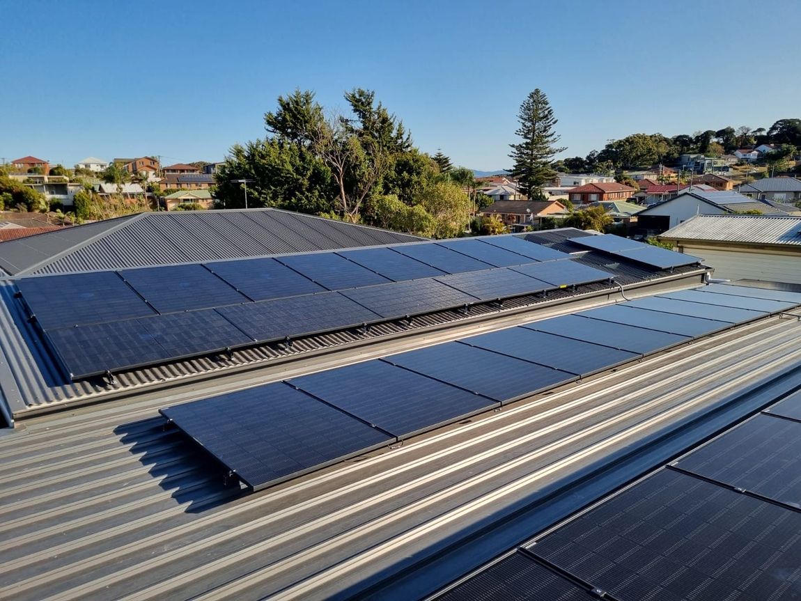 A Man Holding A Drill Is Installing Solar Panels On A Roof — Solarblu Pty Ltd In Dapto, NSW