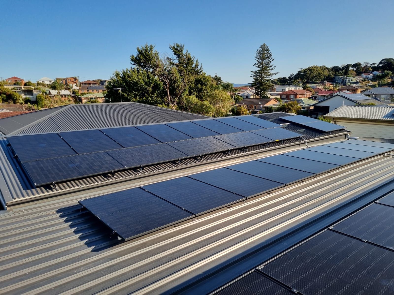 A Man Holding A Drill Is Installing Solar Panels On A Roof — Solarblu Pty Ltd In Dapto, NSW