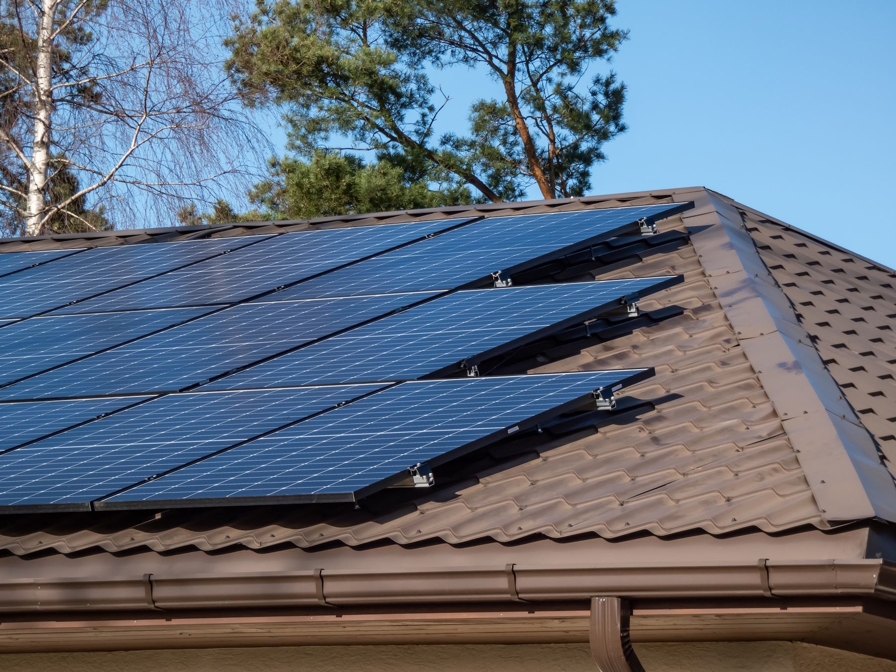 A Man Is Installing Solar Panels On A Roof — Solarblu Pty Ltd In Woonona, NSW