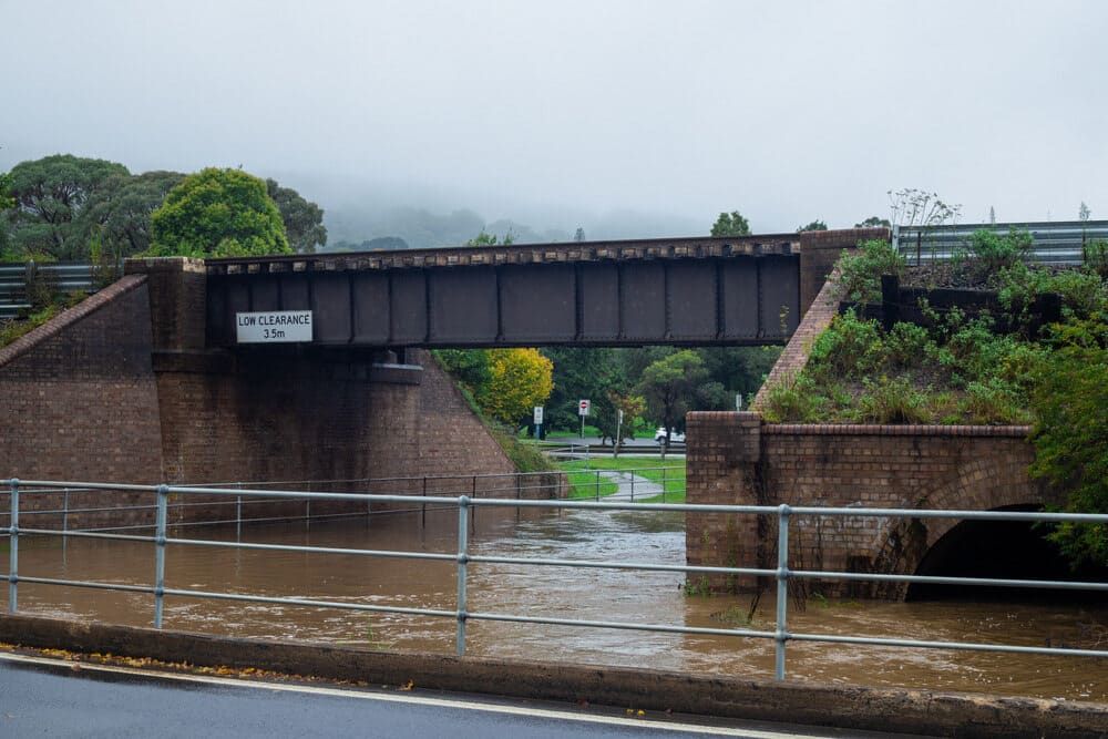 A Bridge Over A Flooded River With A Sign On It — Solarblu Pty Ltd In Mittagong, NSW