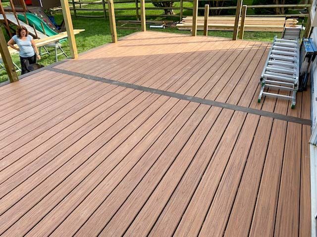A woman is standing on a wooden deck next to a ladder.