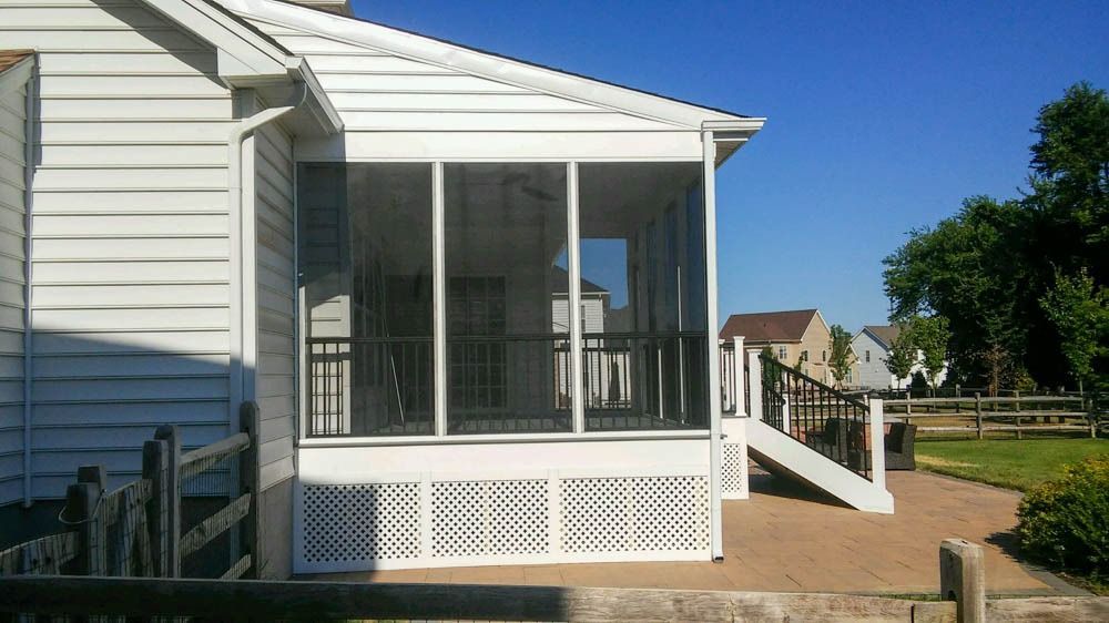 A screened in porch on the side of a white house