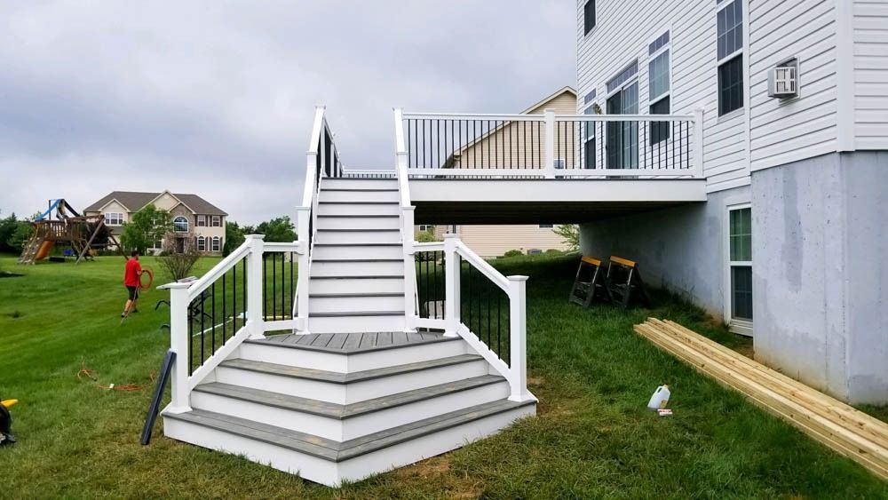A deck with stairs and a railing is being built in the backyard of a house.