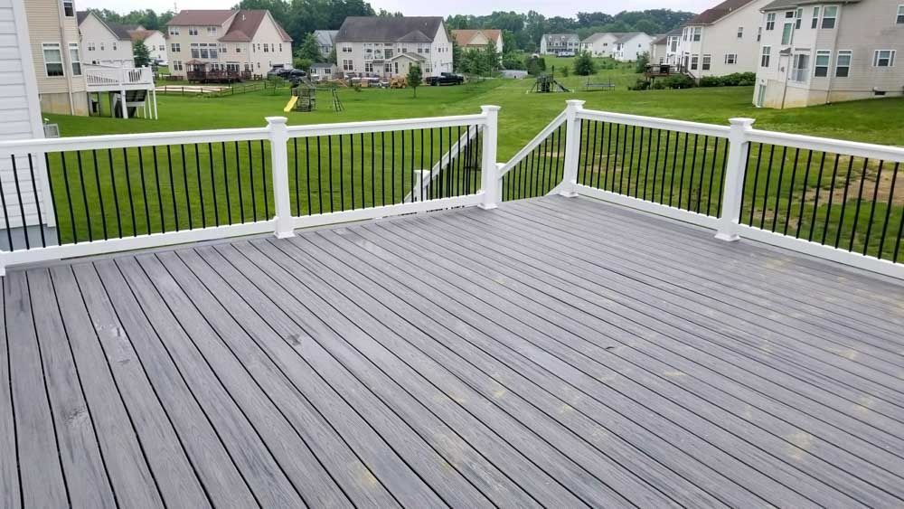 A large deck with a white railing and a view of a residential area.