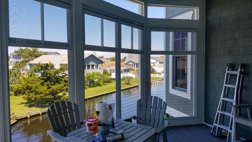 A screened in porch with a table and chairs and a view of a river.
