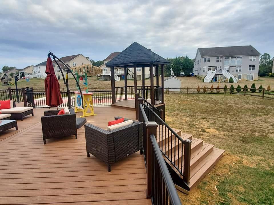 A wooden deck with a gazebo and chairs on it.