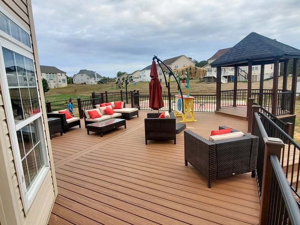 A large deck with a gazebo and lots of furniture on it.