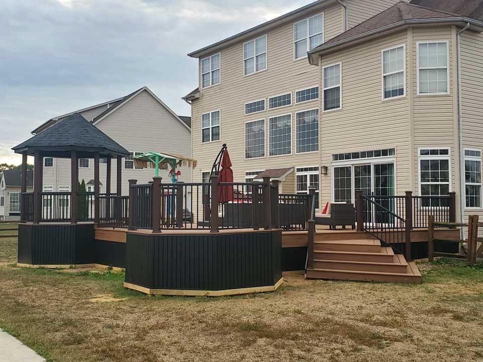 A wooden deck with a gazebo and chairs on it.