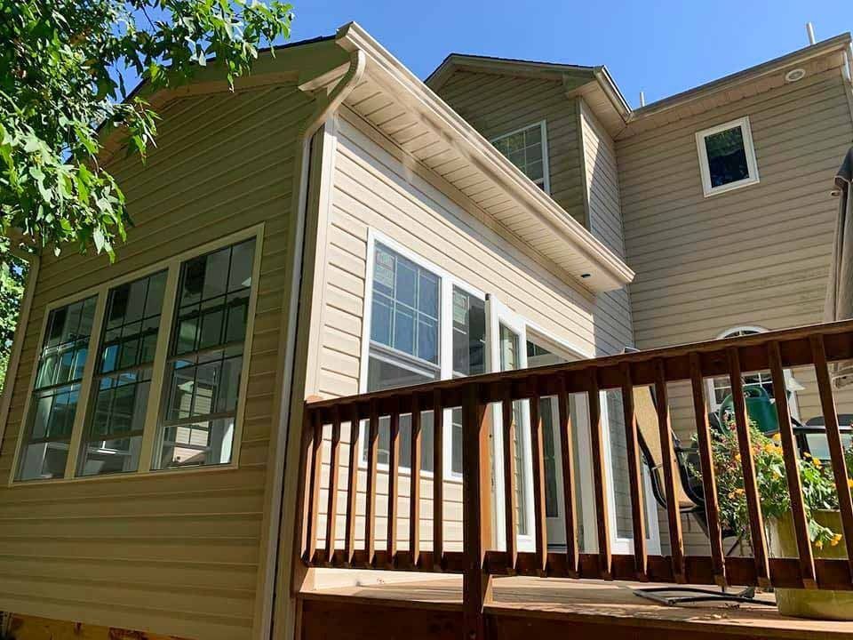 The back of a house with a deck and a lot of windows.