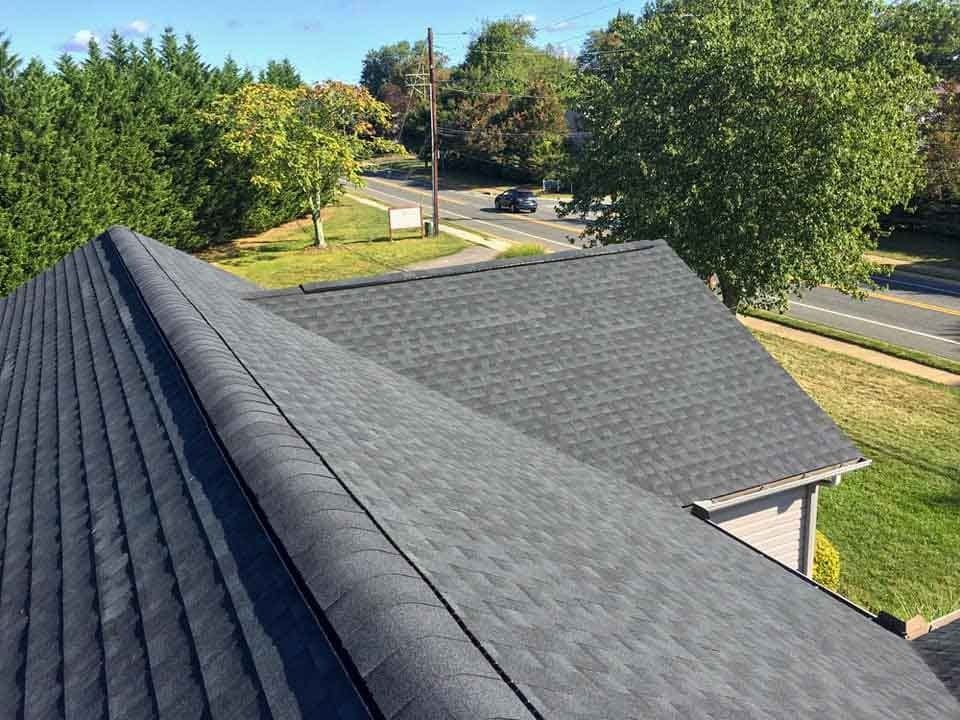 An aerial view of a roof of a house with a black shingle roof.