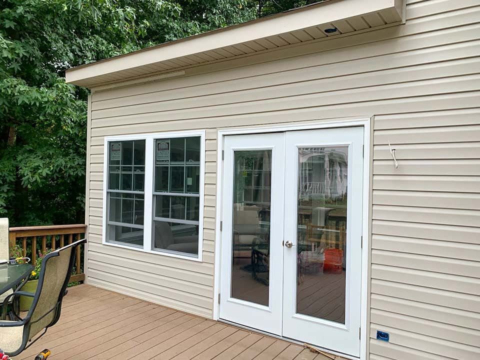 A house with a deck and a large window on the side of it.