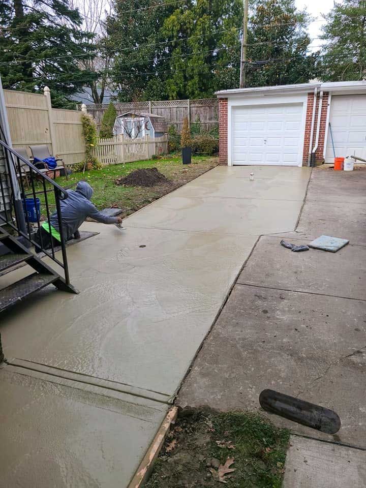 A man is laying on a concrete driveway next to a garage.