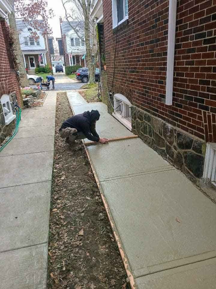 A man is measuring a sidewalk in front of a brick building.