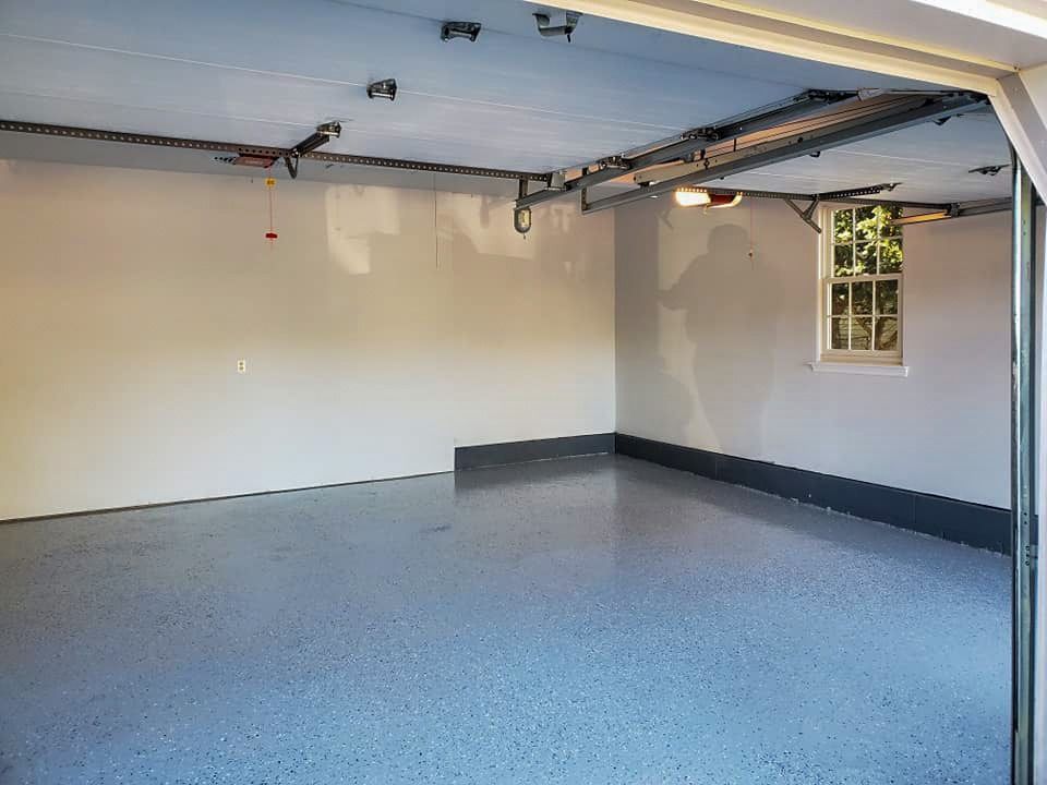 An empty garage with a garage door open and a window.