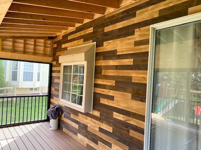A screened in porch with a wooden wall and a window.