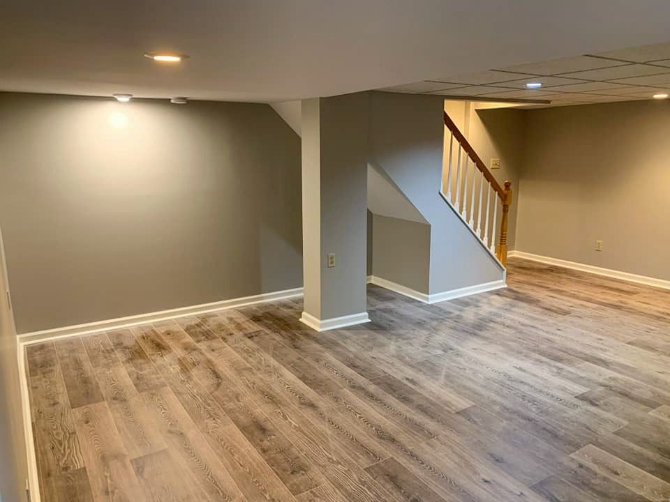 An empty basement with hardwood floors and a staircase.