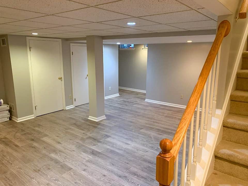An empty basement with hardwood floors and stairs.