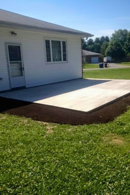 A white house with a concrete patio in front of it.