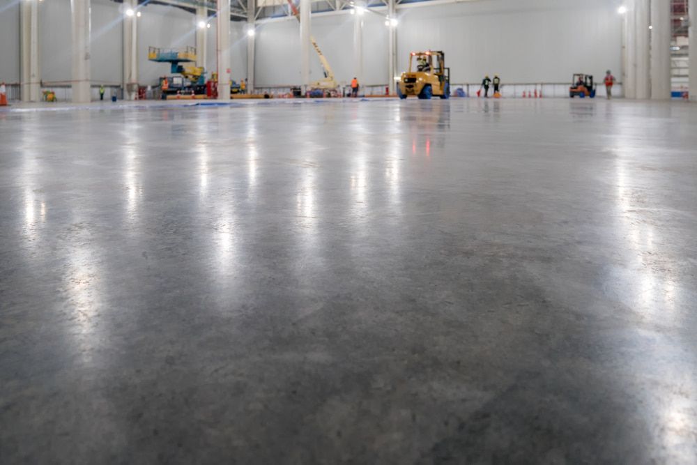 A Large Warehouse With a Shiny Concrete Floor and a Forklift — NHM Painting & Projects Pty Ltd in Ciccone, NT