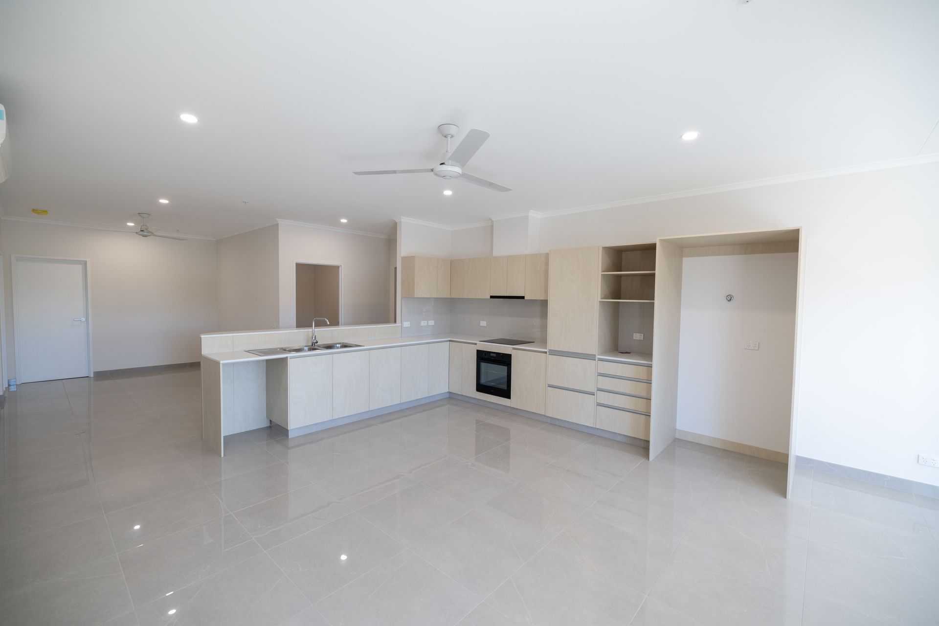 An Empty Kitchen With White Cabinets and a Ceiling Fan  — NHM Painting & Projects Pty Ltd in Ciccone, NT