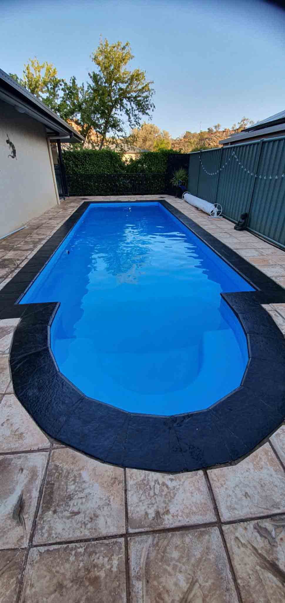 A Large Swimming Pool Filled With Blue Water in a Backyard — NHM Painting & Projects Pty Ltd in Ciccone, NT